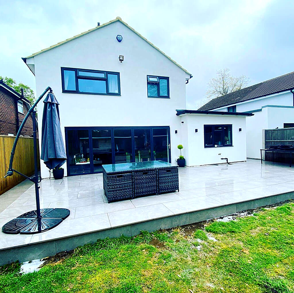 Rendered rear extension with bifold doors opening onto a newly paved patio and lawn