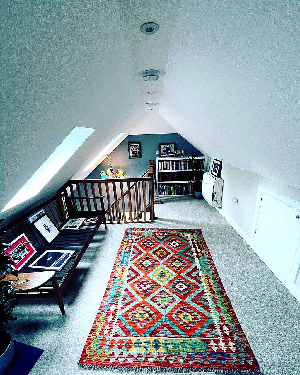 Loft conversion landing with a sloped ceiling, roof window, eaves storage and a patterned rug