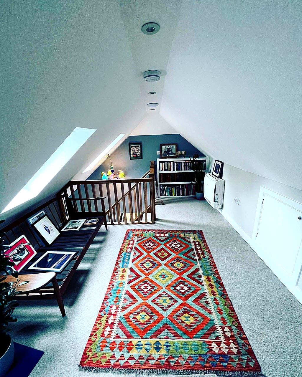 Finished loft conversion with a sloped ceiling, roof window and patterned rug