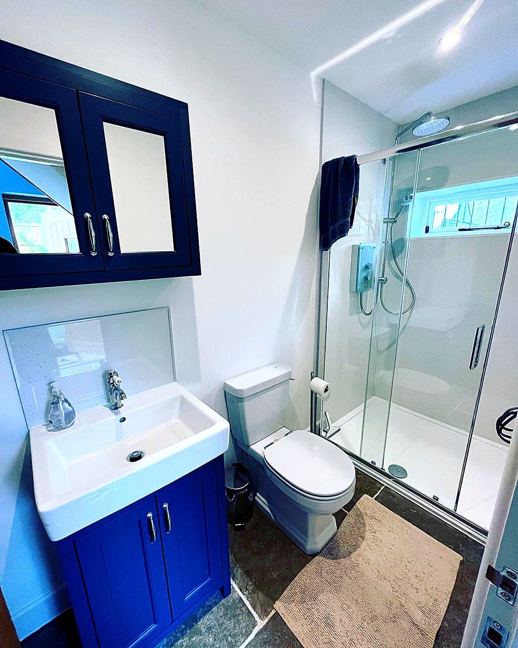 Refitted shower room with a blue vanity unit, mirrored cabinet and a sliding door shower enclosure